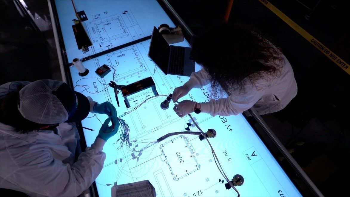 Employees assemble wiring on a wire board.